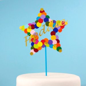 Multicoloured star cake topper with blue stick displayed in plain white cake.