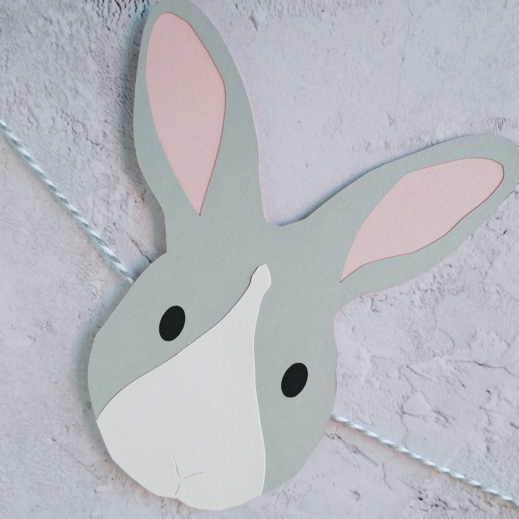 Pale grey easter bunny decoration threaded onto grey and white bakers twine. Bunny has pale pink ears, black oval eyes and a central white nose patch.
