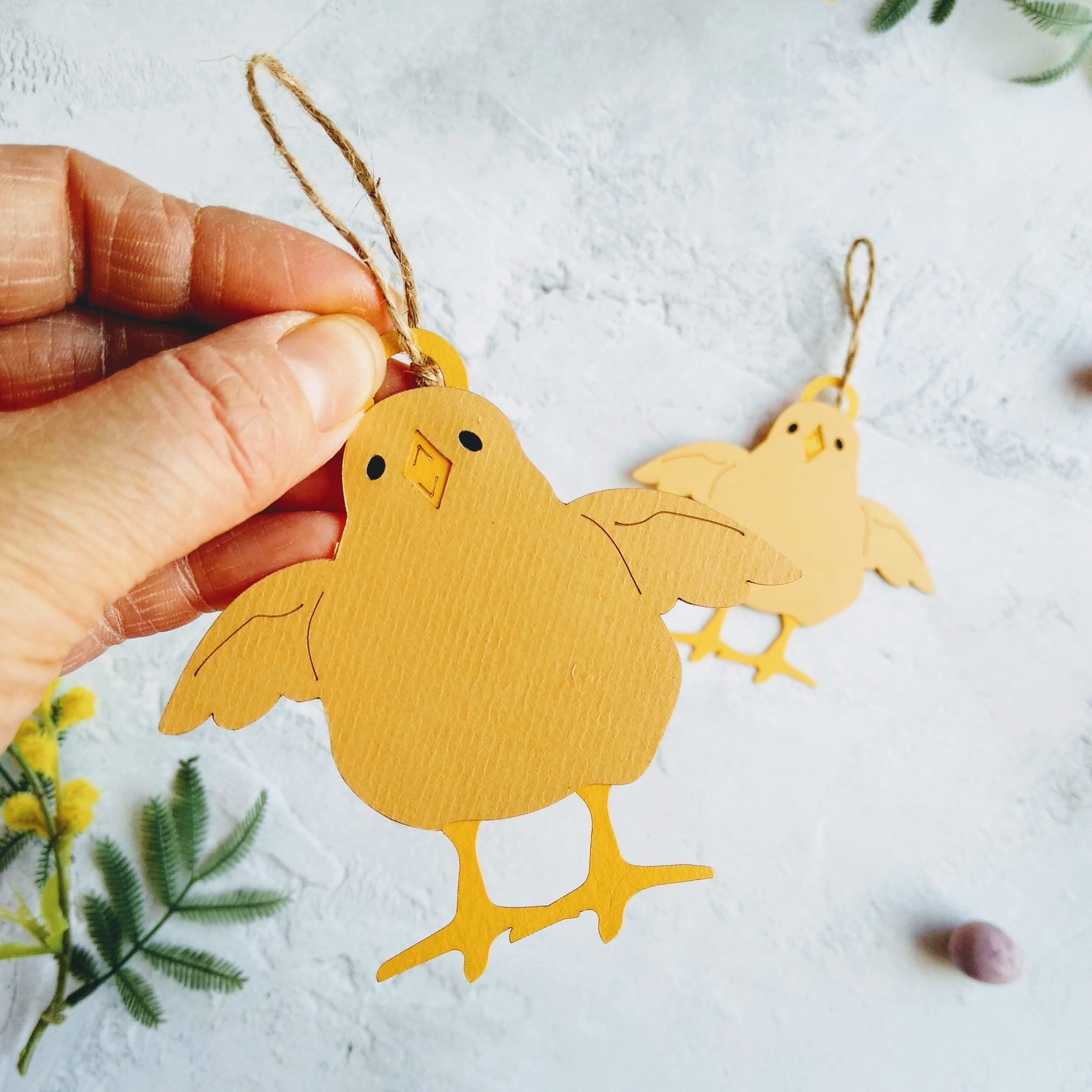 Easter Chick Pair of Hanging Decorations Design 2. One decoration is held in models hand.