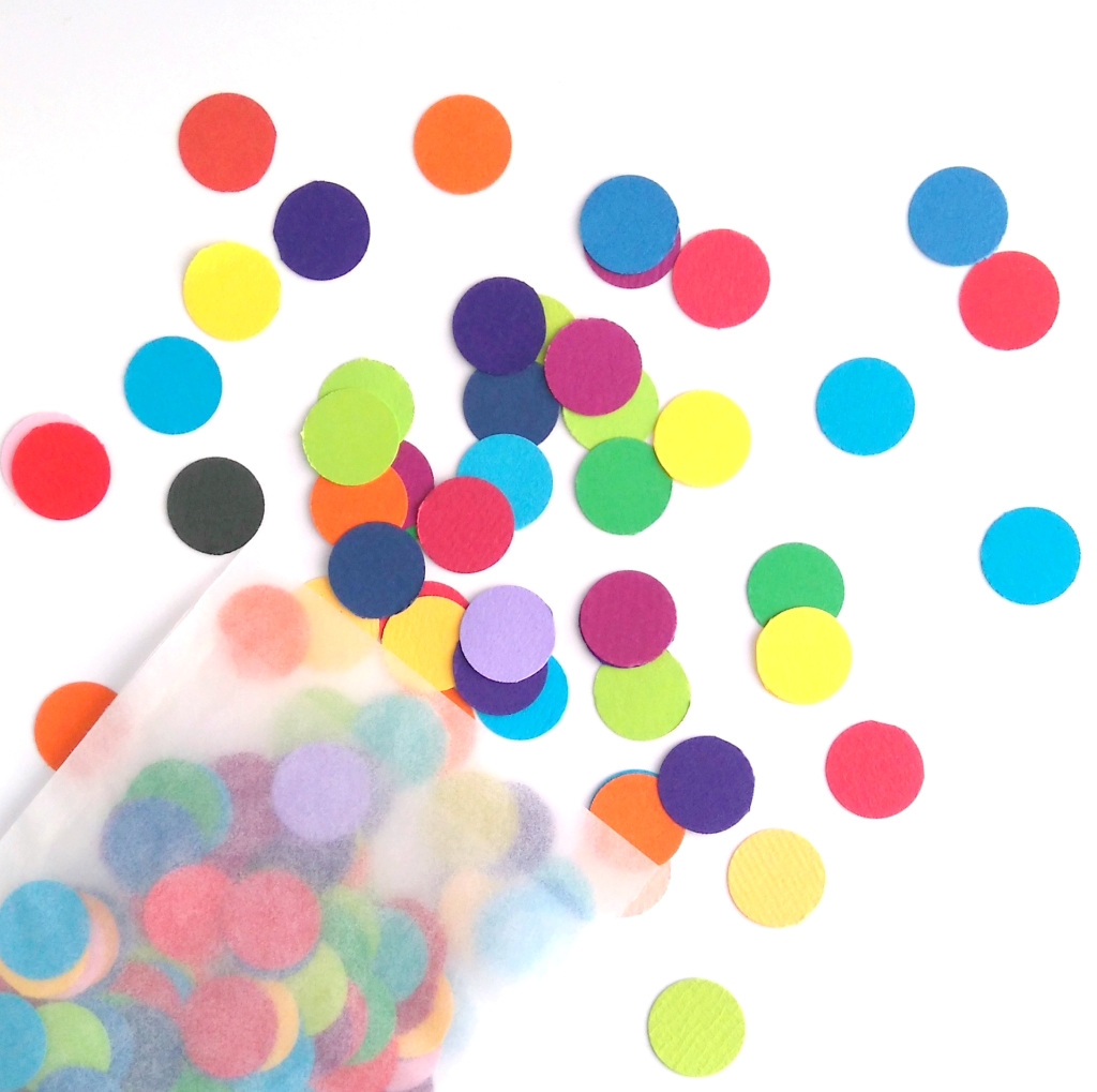 Closeup view of rainbow dot confetti. 1.5cm circles of paper in various shades or red, yellow, blue. green. orange, purple and pink.