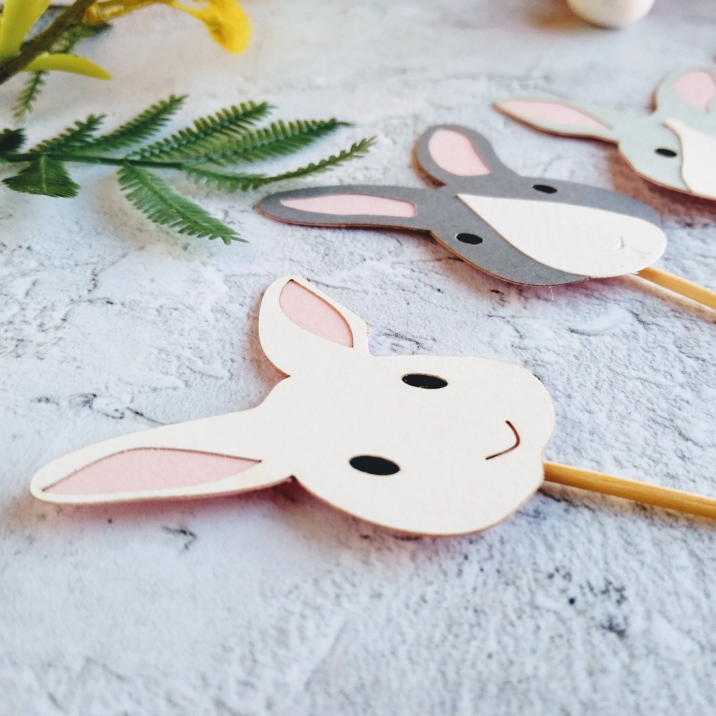 Closeup of white easter bunny cupcake topper, showing small black eyes, a tiny v shape for a nose and pale pink ears.