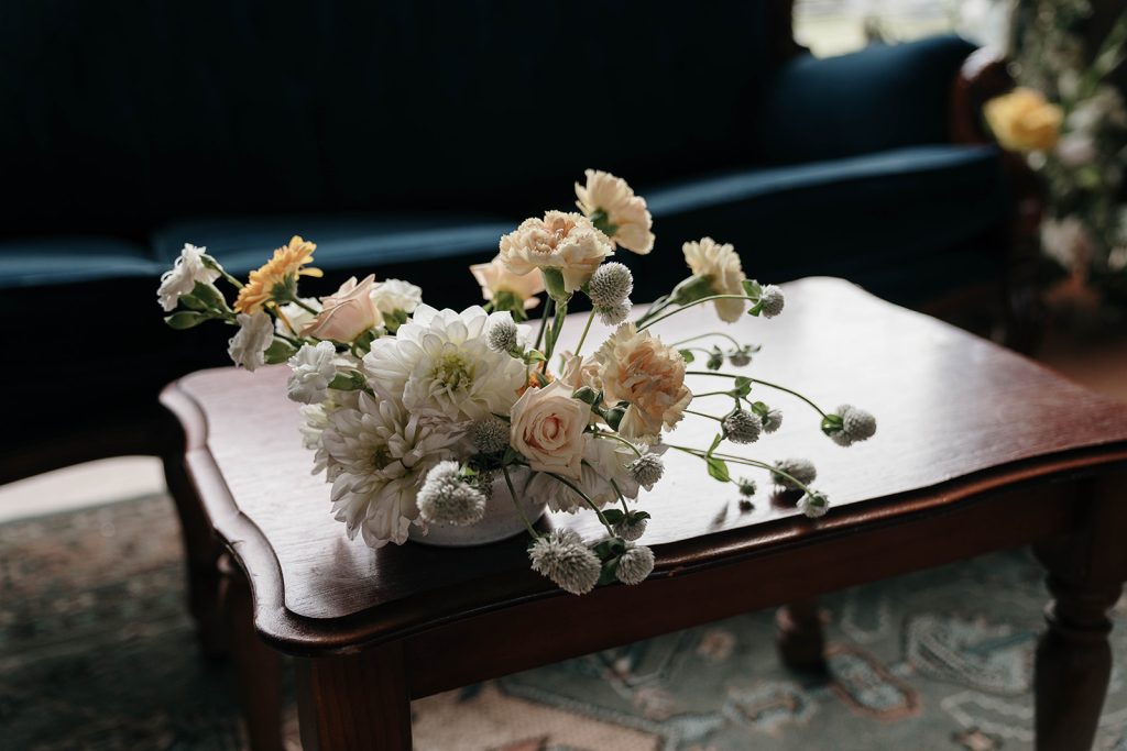 Floral arranagement on coffee table next to blue velvet sofa