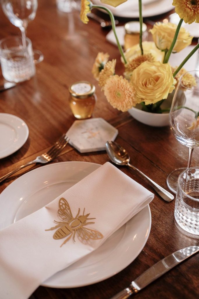 Dark wood wedding reception table with floral arrangement in yellows, peaches and creams