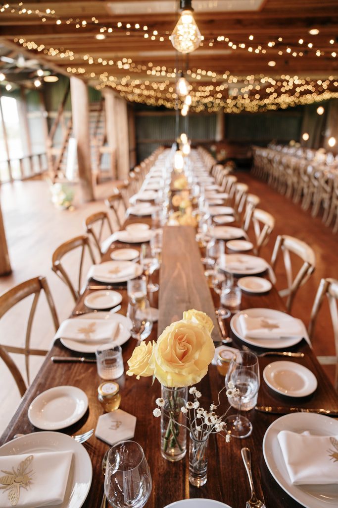 Long table set up for wedding reception with strings of lights across the ceiling