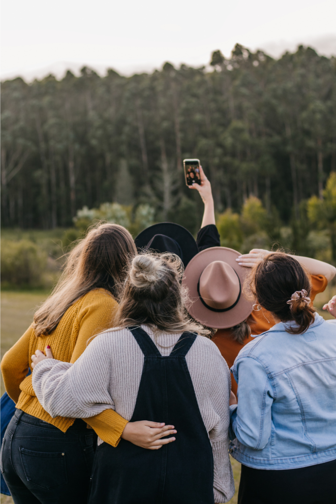 A group of women pose for a selfie together (viewed from behind)