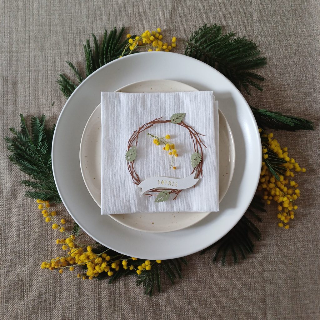 Mimosa flowers and foliage tucked under the edge of layered plates to create a wreath effect.