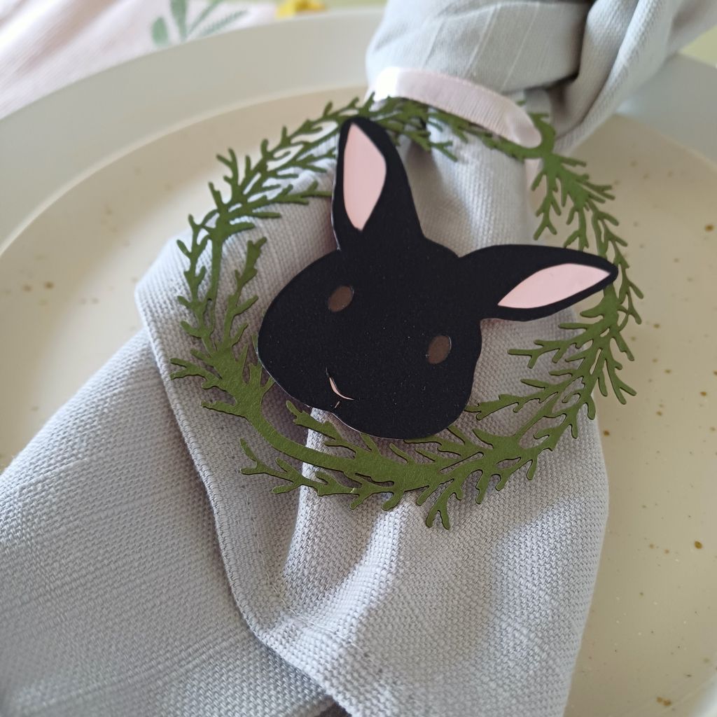 Black Easter Bunny Place Setting is shown tied to knotted brown linen napkin. The decoration is threaded with pale pink gros grain ribbon.